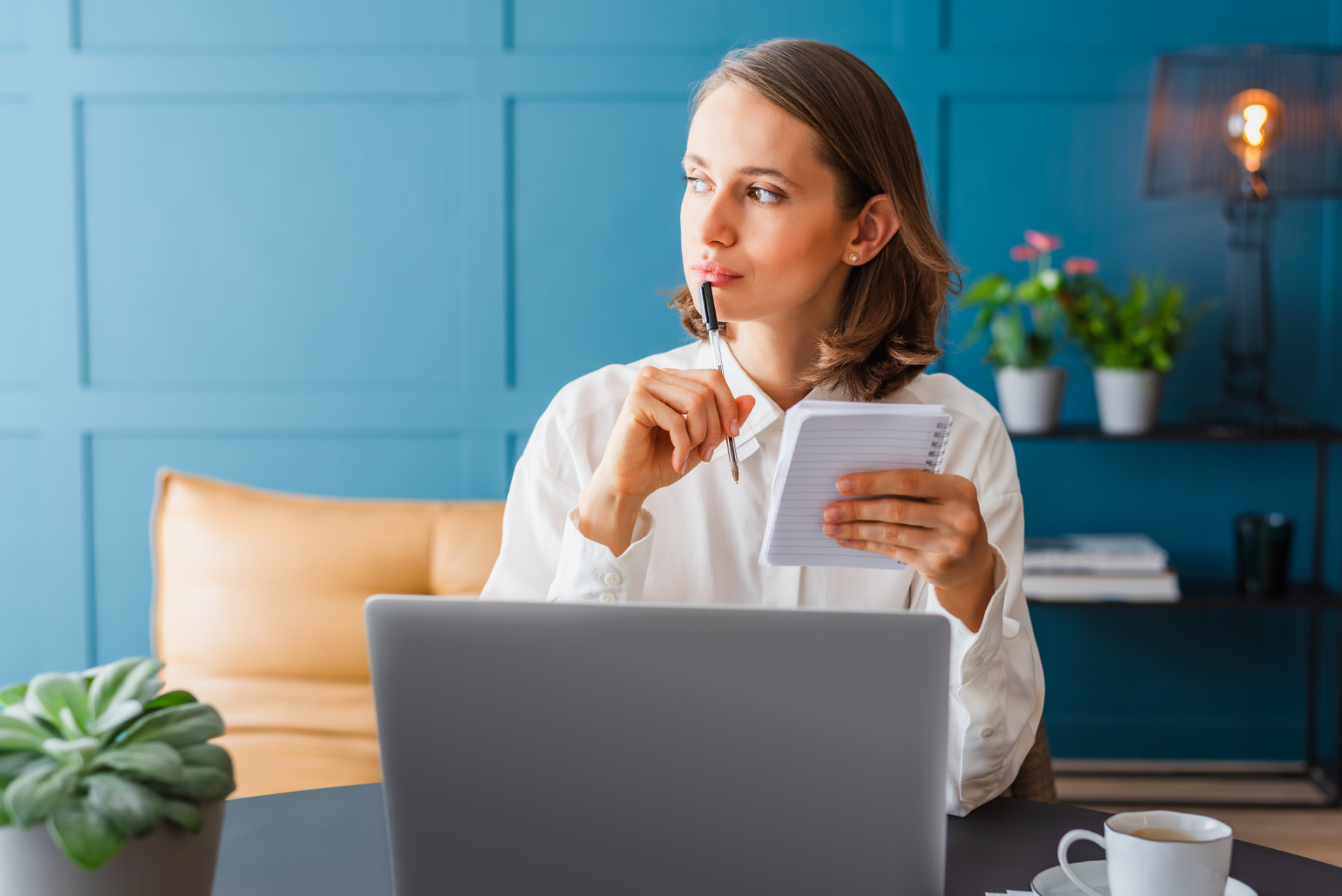 Woman thinking while taking notes in a notebook